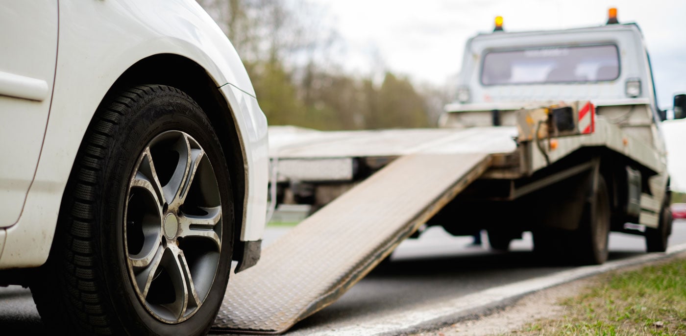 White car being loaded onto a tow truck for vehicle removal